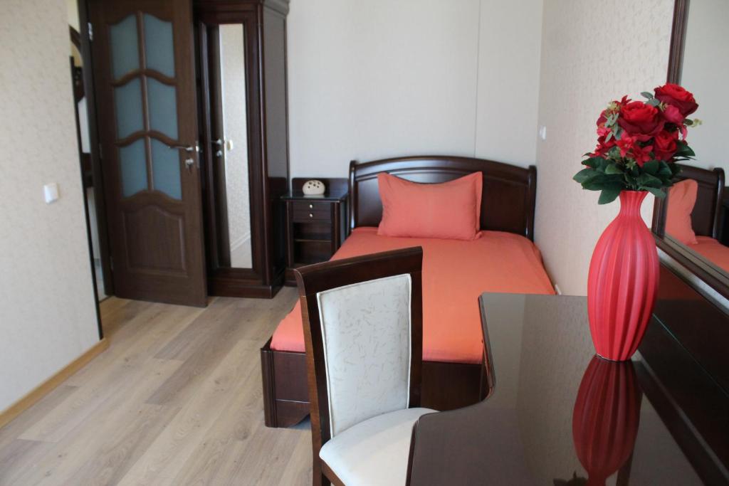 a bedroom with a bed and a vase with roses at Pensiunea Junior in Cluj-Napoca