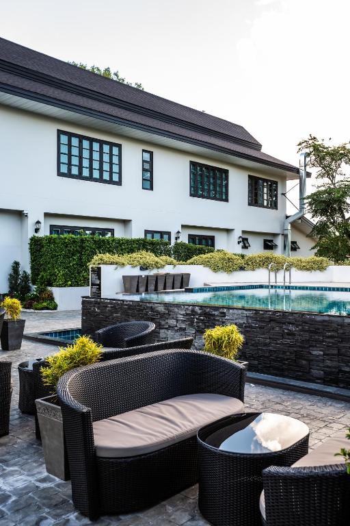 A poolside seating area with wicker sofas and a raised water feature.