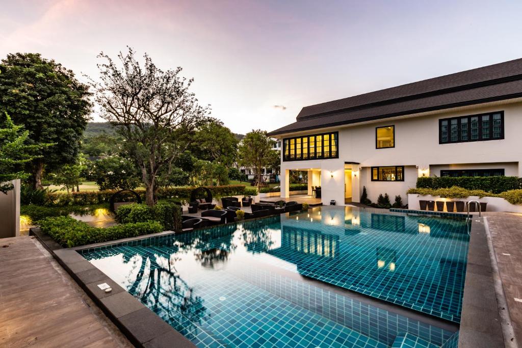 A tiled outdoor pool beside the hotel building and landscaped grounds.