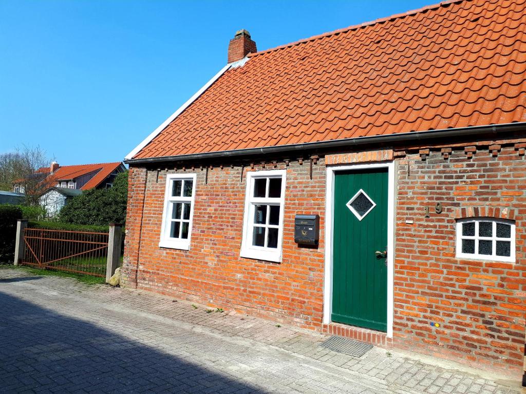 a brick building with a green door on a street at Ferienhaus Anno1875 in Emden