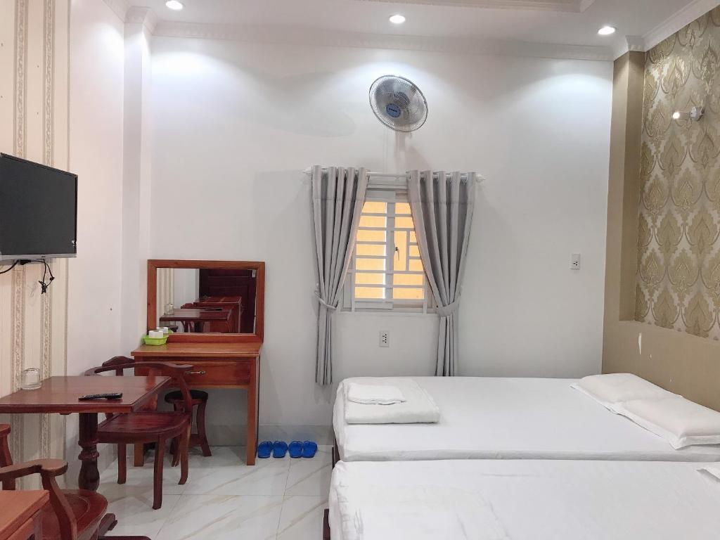 a bedroom with a bed and a desk and a window at KHÁCH SẠN KIM PHỤNG NGÂN in Bình Thủy