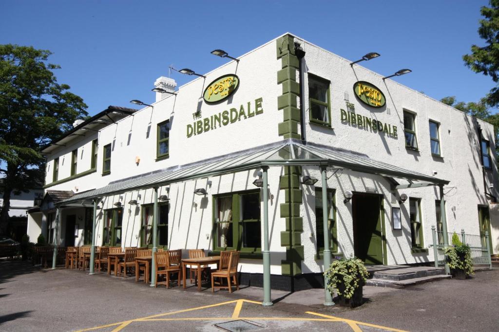 ein weißes Gebäude mit Tischen und Stühlen davor in der Unterkunft The Dibbinsdale Inn in Bromborough