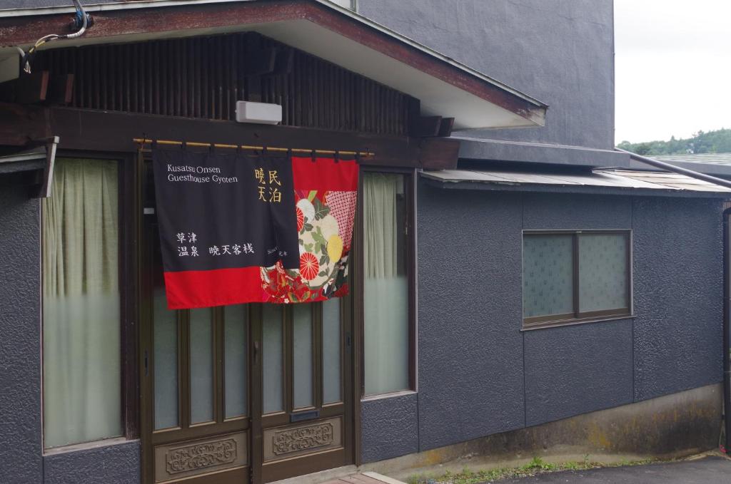 un edificio con una pancarta a un lado. en Kusatsu Onsen Guesthouse Gyoten en Kusatsu