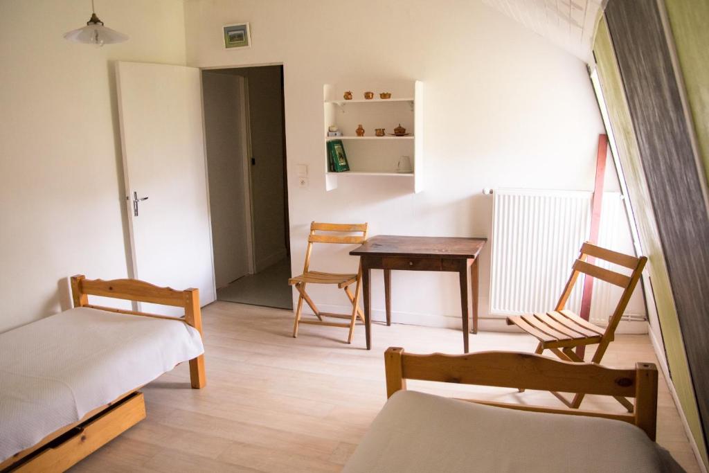 a room with two beds and a table and chairs at Chambres d'hôtes de charme Le Pradel in Monceaux-sur-Dordogne