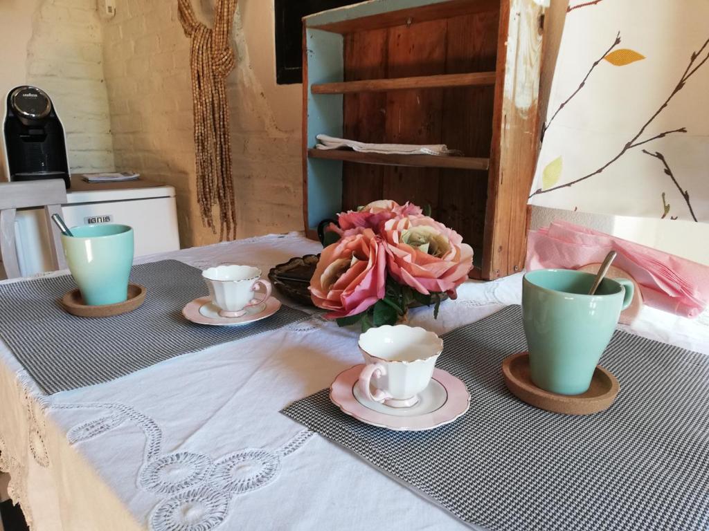 una mesa con dos tazas y un jarrón de flores en Bed and Breakfast Aurora, en Sarzana