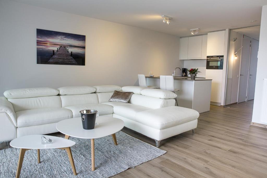 a living room with a white couch and a table at Design appartement Zeelaan Koksijde in Koksijde