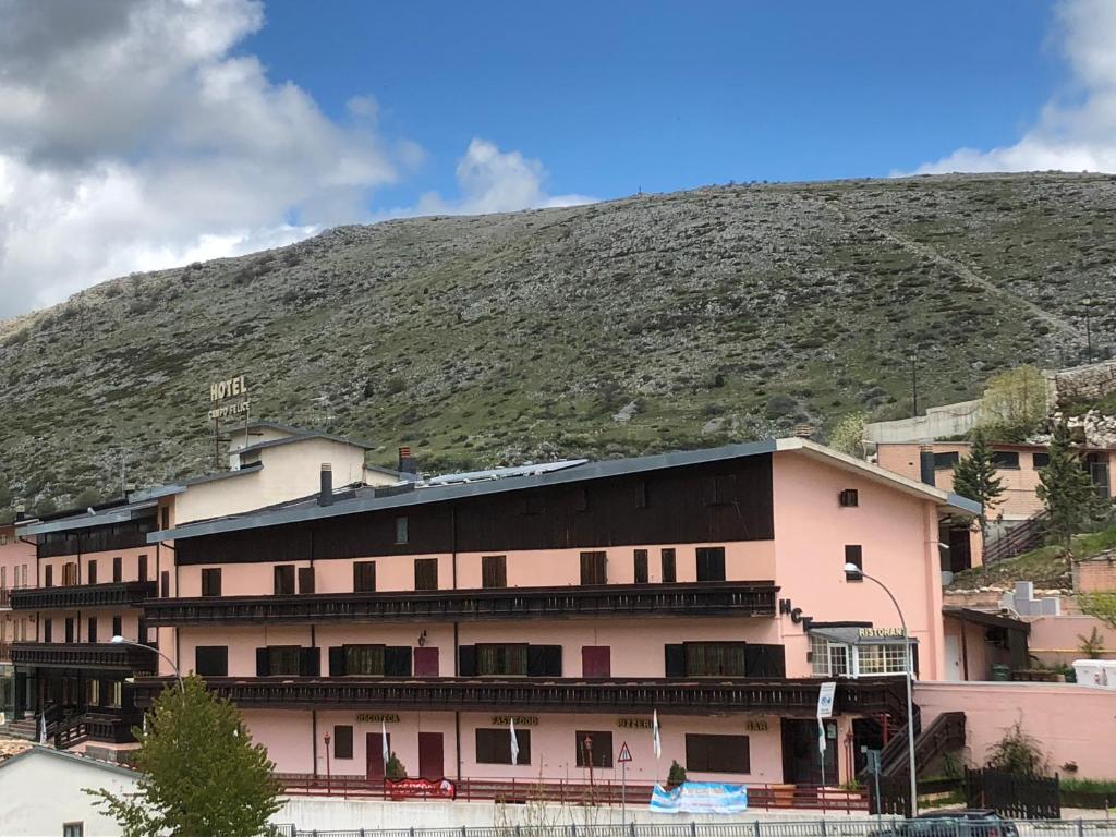 a pink building with a mountain in the background at Hotel Campo Felice in Lucoli Alto