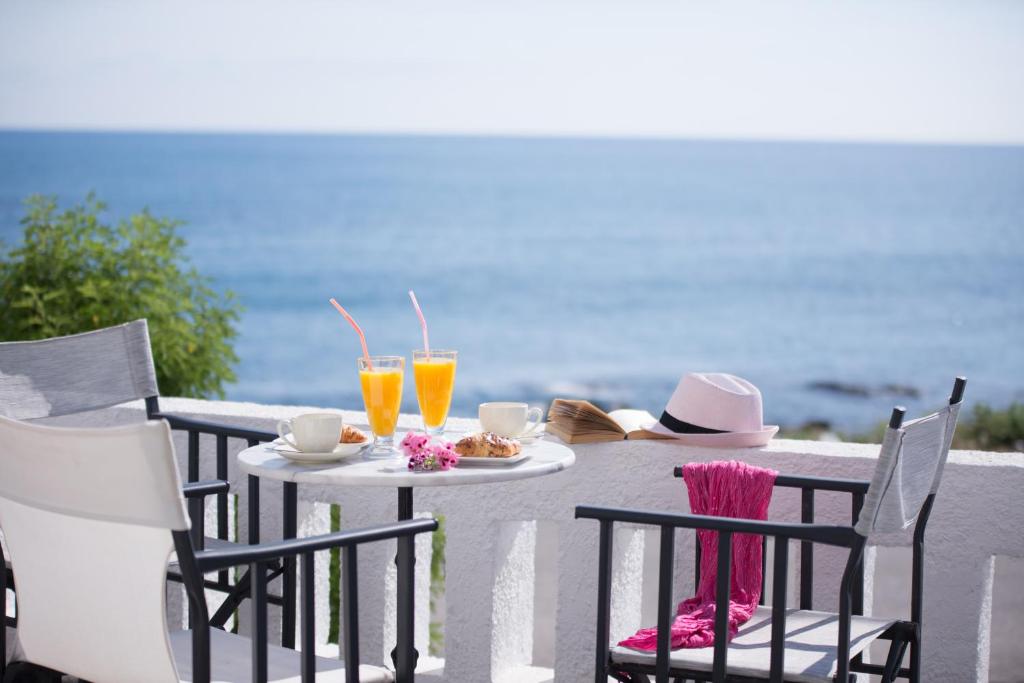 einen Tisch mit 2 Stühlen und einen Tisch mit Getränken in der Unterkunft Arlen Beach Hotel in Hersonissos