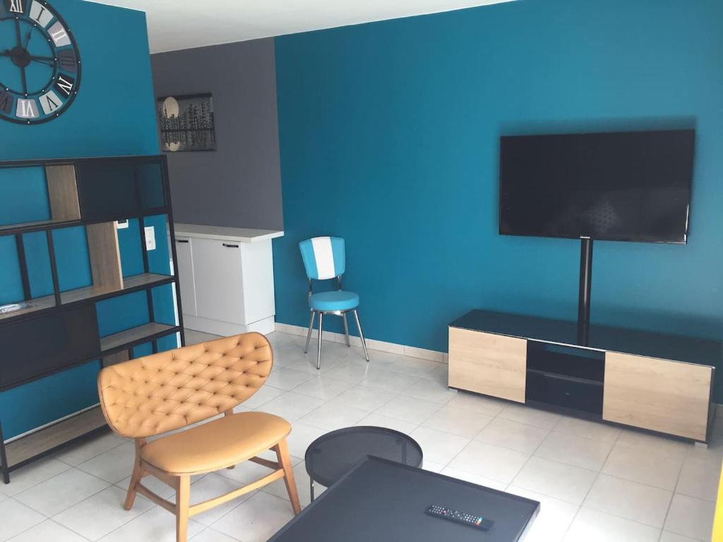 een woonkamer met een tv aan een blauwe muur bij Résidence Studio Grand Luxe Wifi parking privé in Vaulx-en-Velin