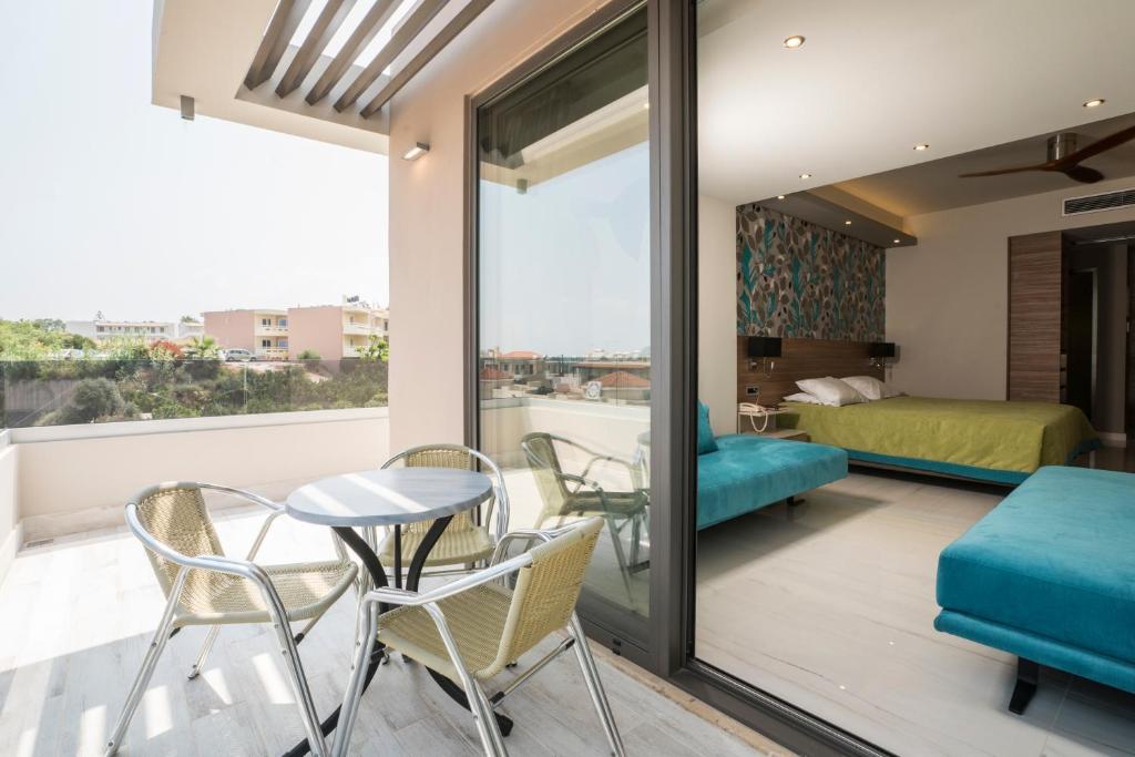 a room with a balcony with a bed and a table and chairs at Atrion Resort Hotel in Agia Marina Nea Kydonias