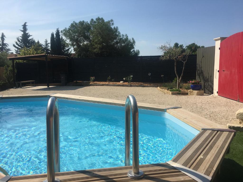 a swimming pool with a wooden deck and a bench at chez ma mie in Théziers