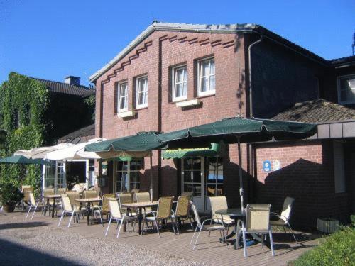 a group of chairs and tables with umbrellas outside a building at Hotel Zur Buche in Bockhorn