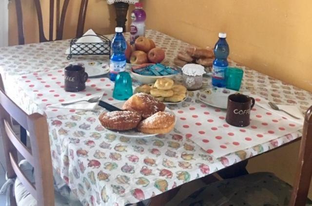 una mesa con mantel con donuts y botellas de agua en Il Melograno B&B, en Albiano