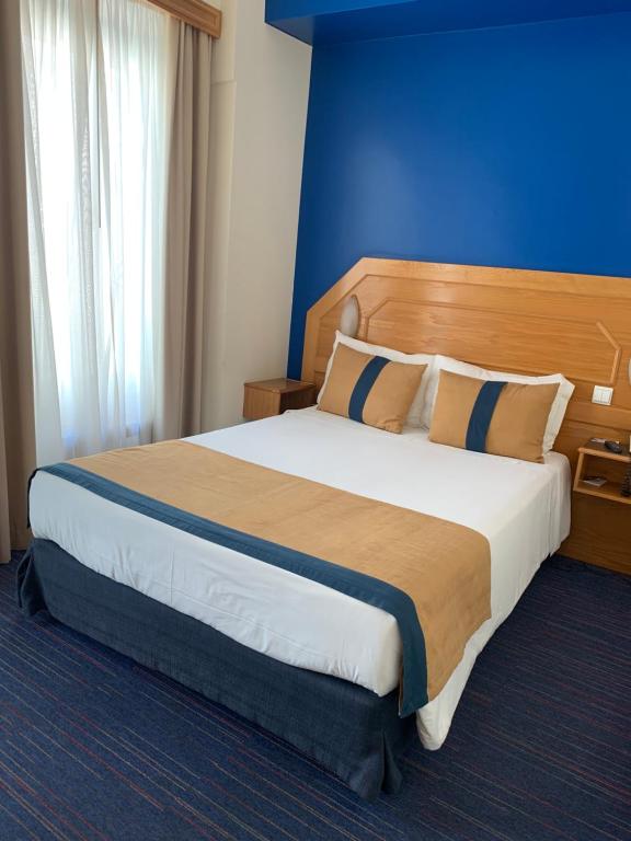 a bedroom with a large bed with a blue wall at Hotel Do Chile in Lisbon