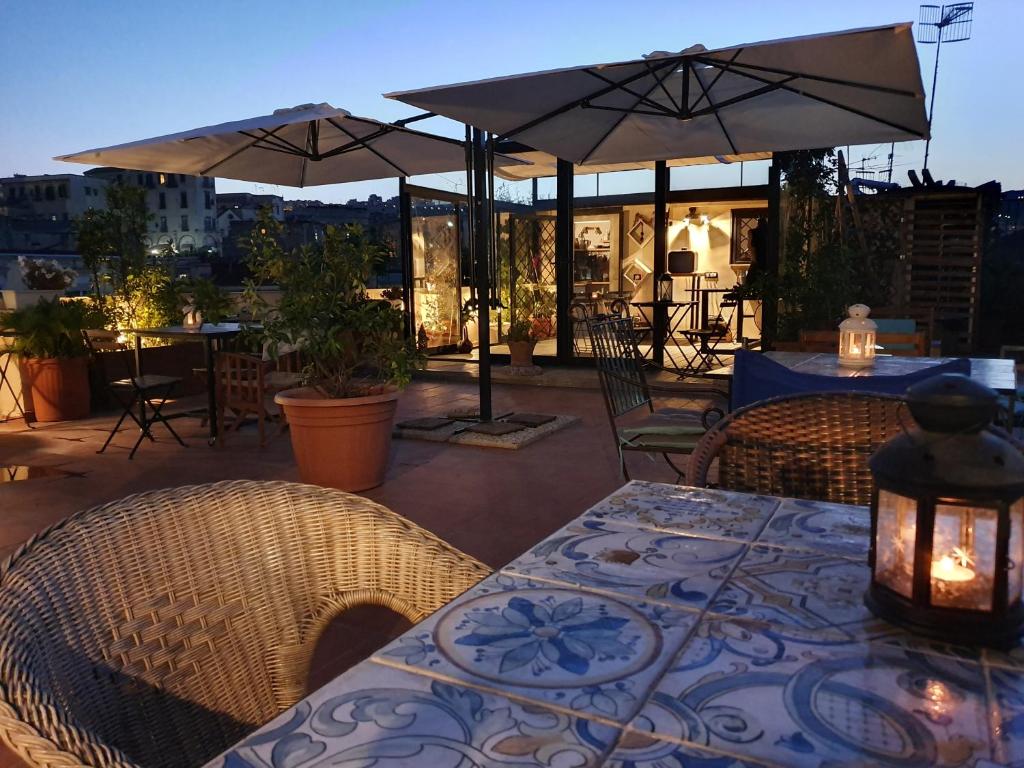 eine Terrasse mit einem Tisch, Stühlen und Sonnenschirmen in der Unterkunft The Spanish Palace Rooms, Suites Apartments & Terraces in Neapel