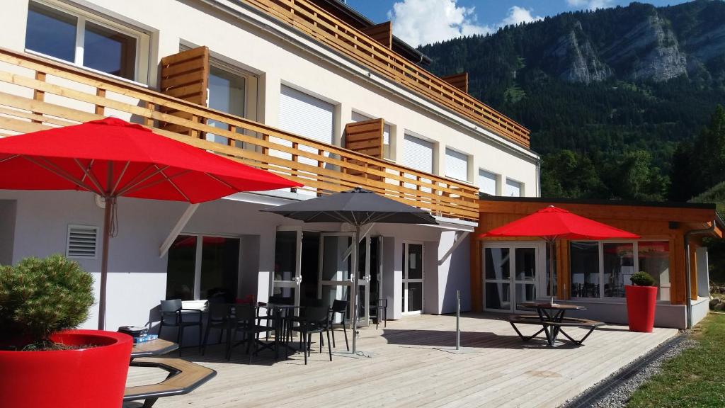 a patio with tables and umbrellas in front of a building at Domaine de Maravant - Centre de vacances in Thollon