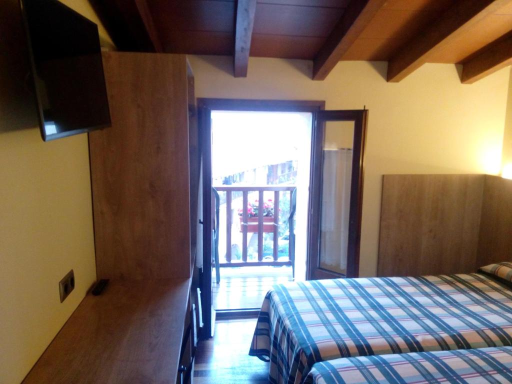 a bedroom with a bed and a door to a balcony at CAN MENCIÓ - Plaça Major in Santa Pau