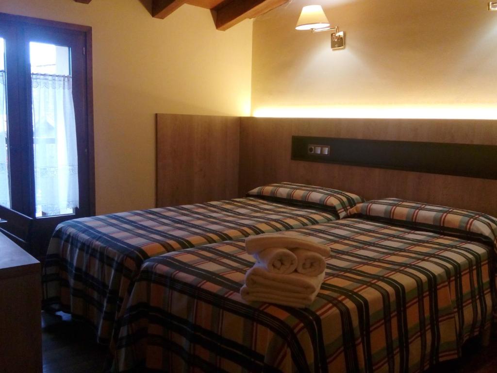 a hotel room with a bed with a towel on it at CAN MENCIÓ - Plaça Major in Santa Pau