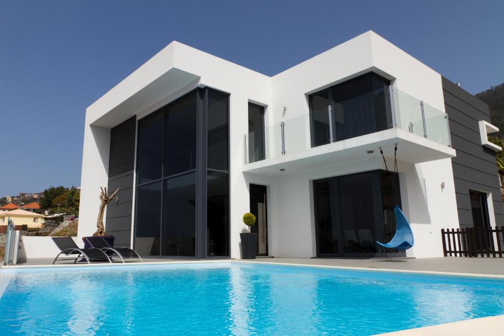 eine Villa mit einem Pool und einem Haus in der Unterkunft Luxo & Conforto in Calheta