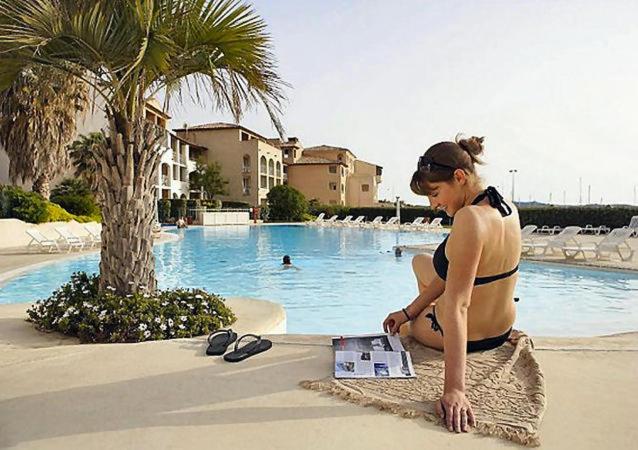 une femme en bikini assise devant une piscine dans l'établissement Vue sur la mer, plage à 50m, à Six-Fours-les-Plages
