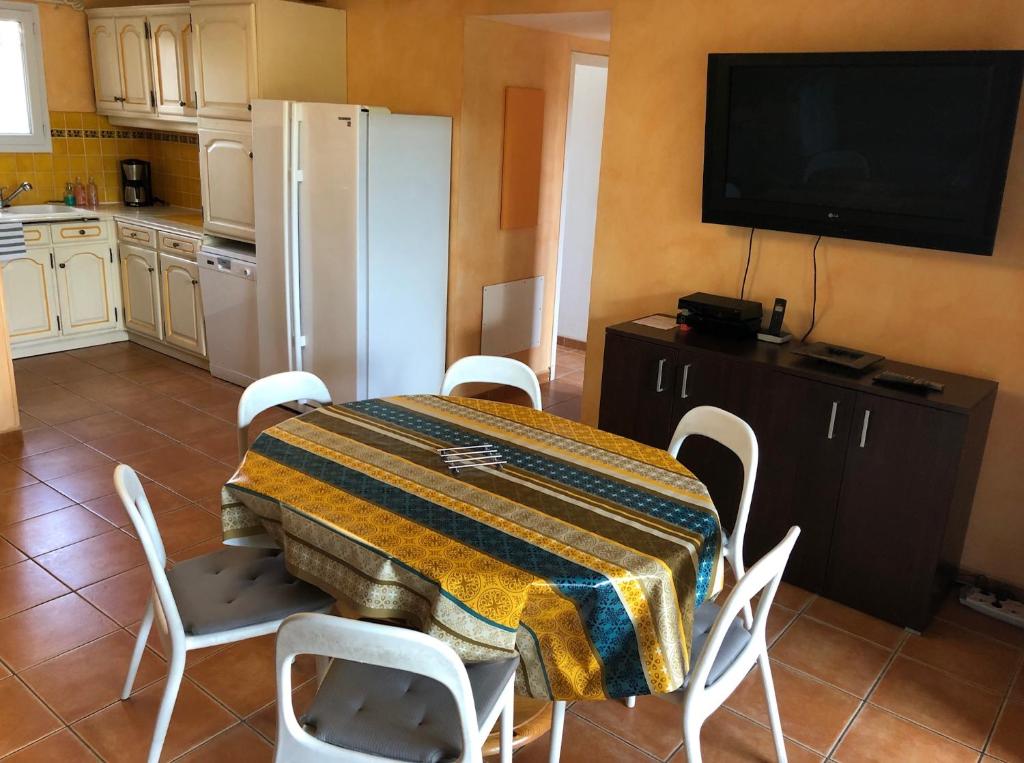 eine Küche mit einem Tisch mit Stühlen und einem TV in der Unterkunft Appartement dans la résidence LES MAZETS DE CAMARGUE in Arles