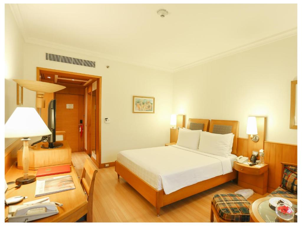 a bedroom with a large white bed and a table at Trident Chennai in Chennai