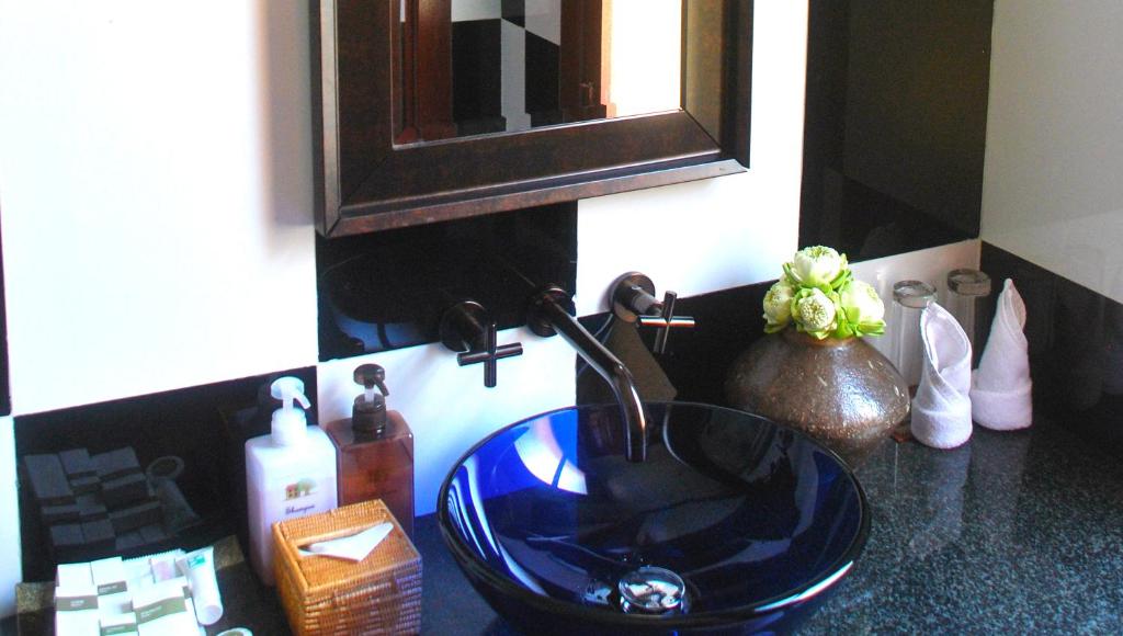 a bathroom counter with a blue sink and a mirror at La Rivière d' Angkor Resort in Siem Reap