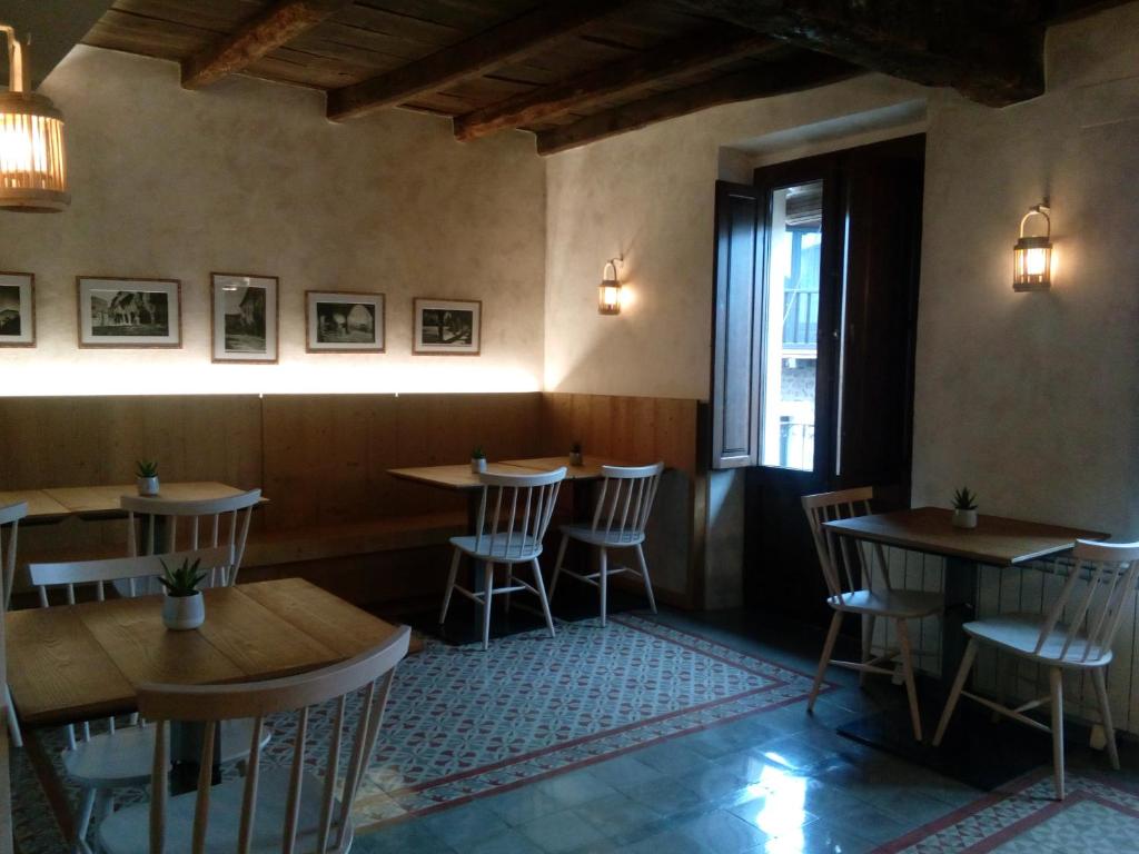 a restaurant with wooden tables and chairs and a window at CAN MENCIÓ - Plaça Major in Santa Pau
