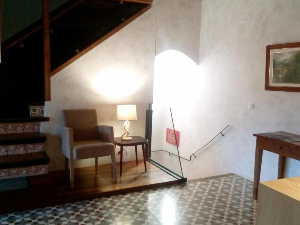 a room with a chair and a lamp and a table at CAN MENCIÓ - Plaça Major in Santa Pau