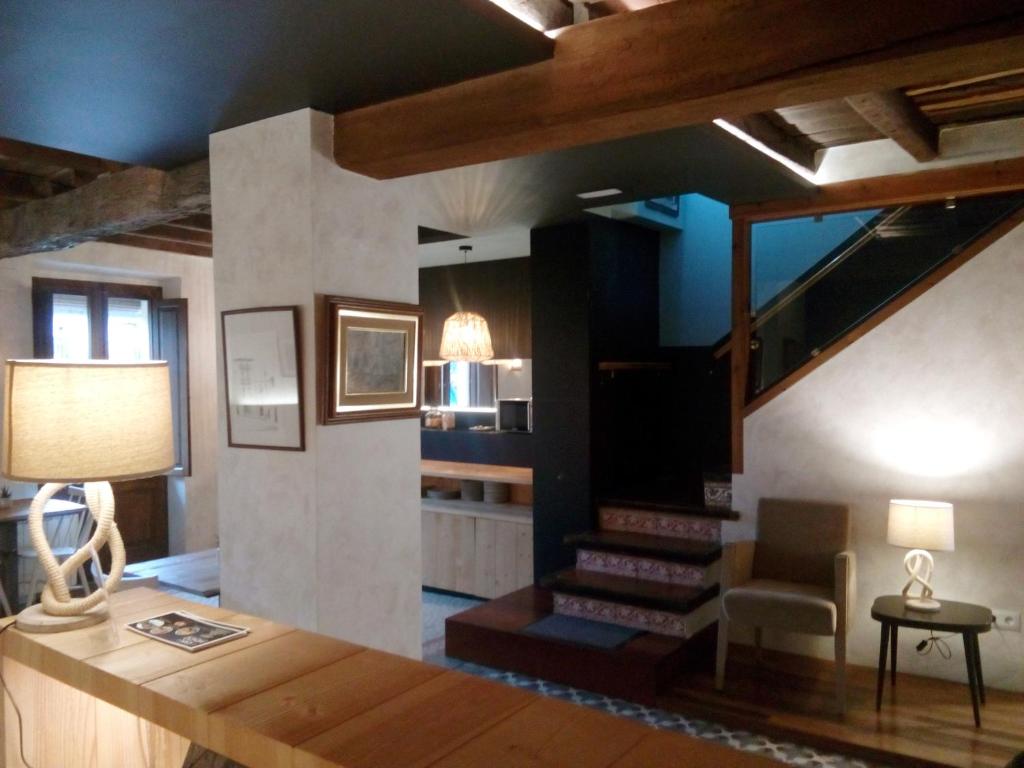 a living room with a staircase with a chair and a lamp at CAN MENCIÓ - Plaça Major in Santa Pau