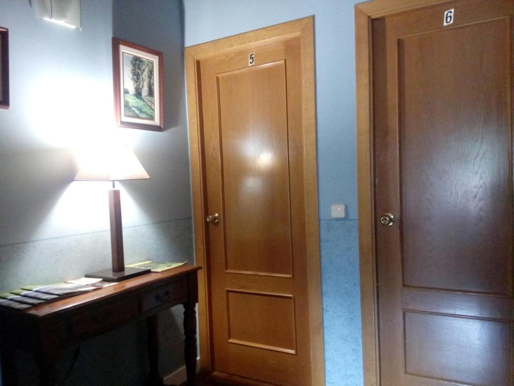 a room with a wooden door and a desk with a lamp at CAN MENCIÓ - Plaça Major in Santa Pau