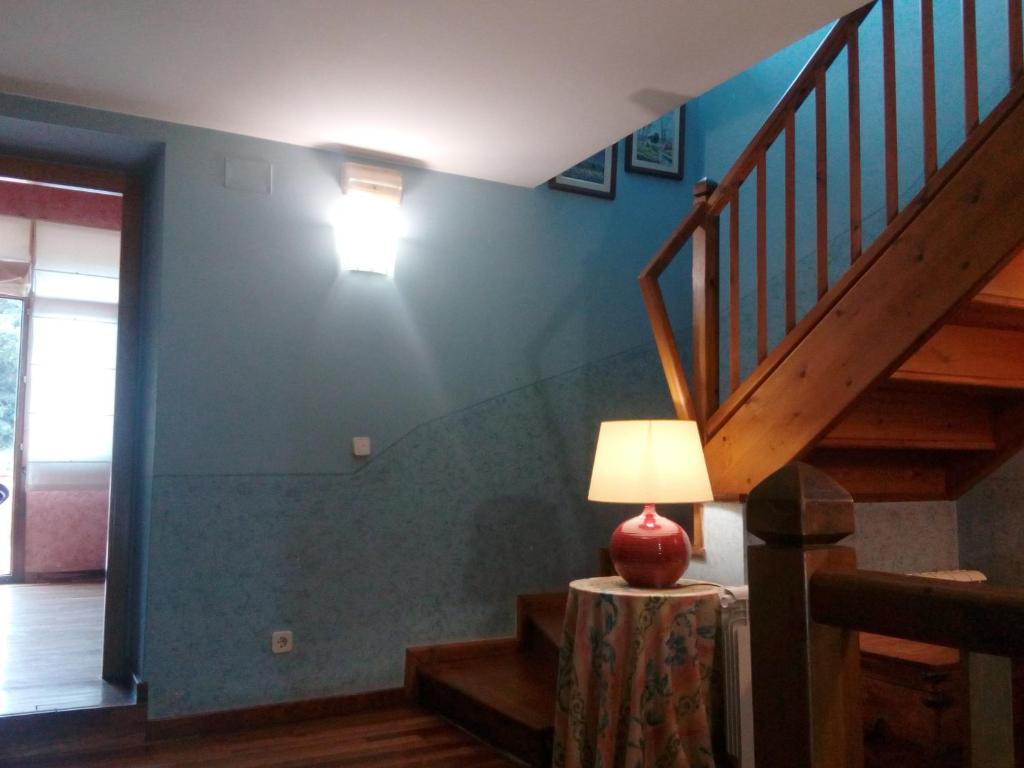 a room with a staircase and a lamp on a table at CAN MENCIÓ - Plaça Major in Santa Pau