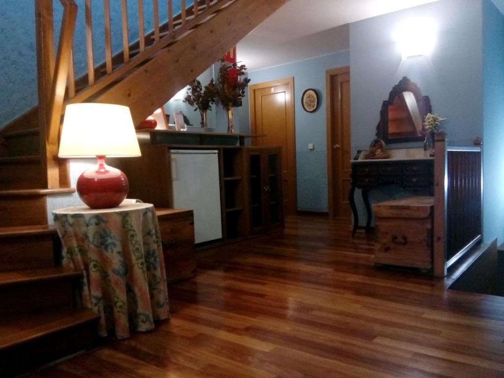 a living room with a staircase and a table with a lamp at CAN MENCIÓ - Plaça Major in Santa Pau