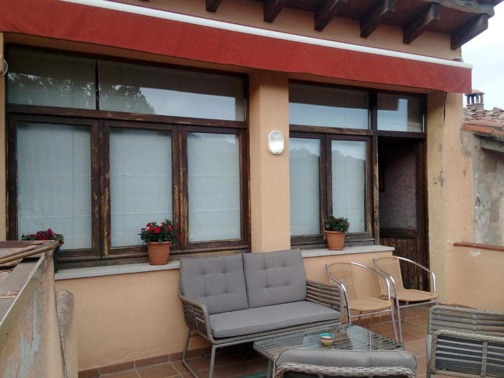 a patio with a couch and chairs and windows at CAN MENCIÓ - Plaça Major in Santa Pau