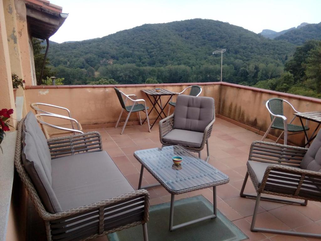 a balcony with chairs and tables and a view of mountains at CAN MENCIÓ - Plaça Major in Santa Pau
