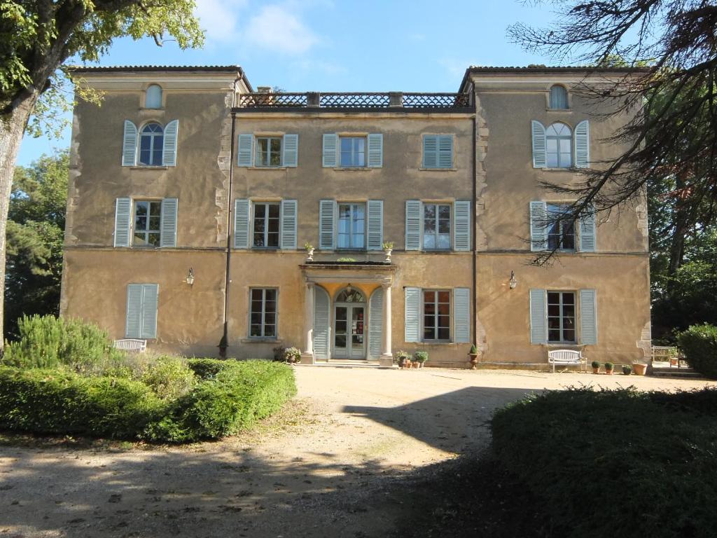 une vieille maison en pierre avec un arbre en face de celle-ci dans l'établissement Chateau des Poccards, à Hurigny