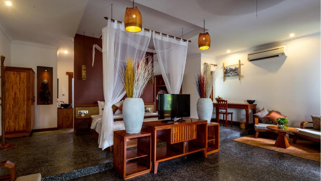 a living room with a tv and vases on a table at La Rivière d' Angkor Resort in Siem Reap
