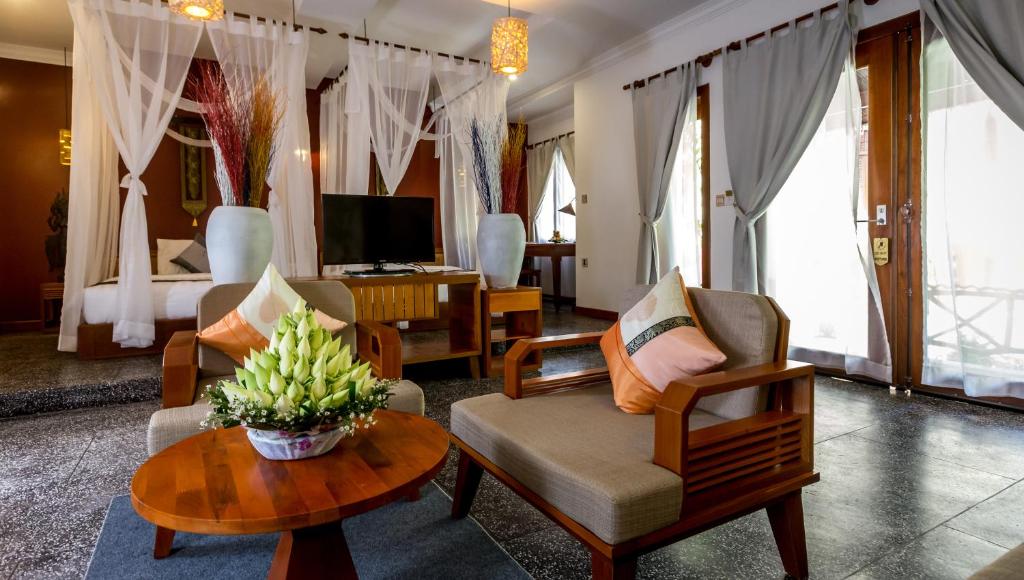a living room with a couch and chairs and a tv at La Rivière d' Angkor Resort in Siem Reap