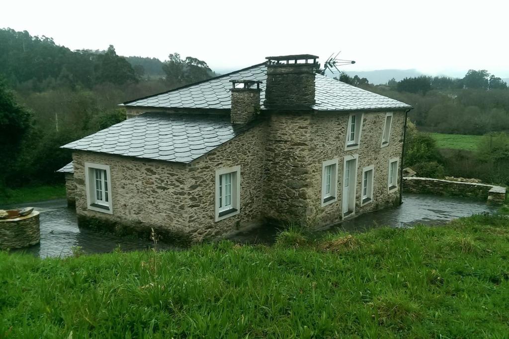 una casa de piedra en medio de un campo en Casa Rural Ortigueira, en A Coruña
