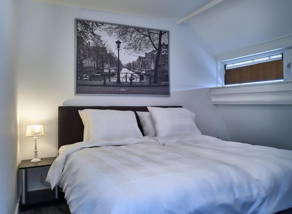 a bedroom with a white bed and a picture on the wall at Sleep Inn Amsterdam in Amsterdam