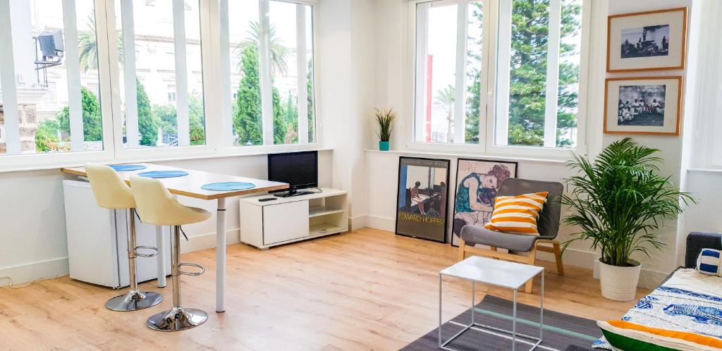 a living room with a table and chairs and windows at Luz de Cádiz in Cádiz