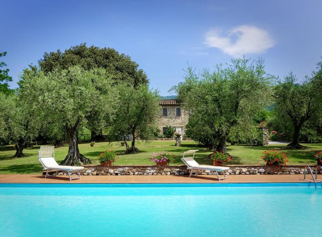 uma piscina com duas cadeiras e um edifício em Villa Casa Tonio em Valgiano