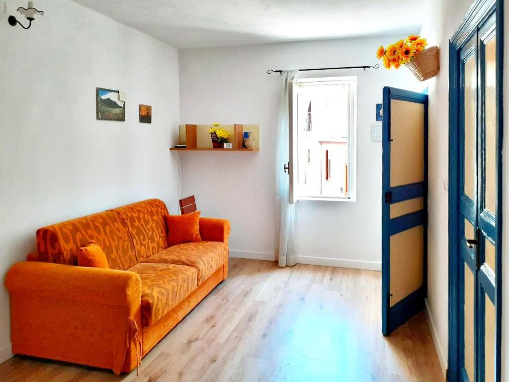 an orange couch in a living room with a window at Don Vito's Apartments in Castellammare del Golfo