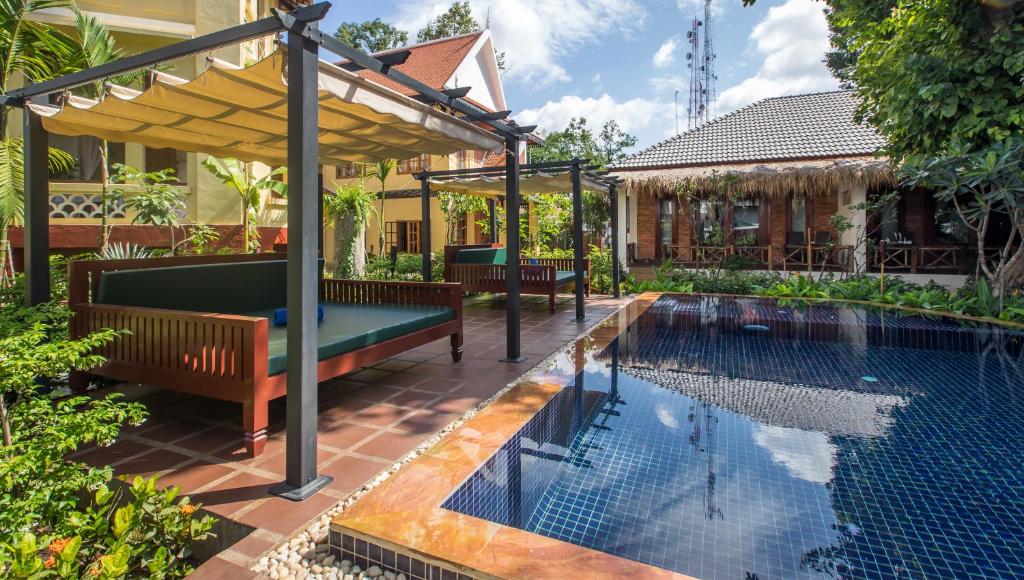 a swimming pool with a pergola next to a house at La Rivière d' Angkor Resort in Siem Reap