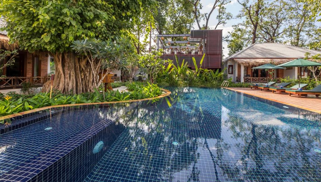 a swimming pool in front of a house at La Rivière d' Angkor Resort in Siem Reap