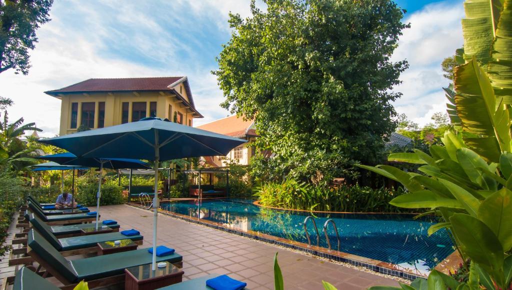 a pool at a resort with chairs and an umbrella at La Rivière d' Angkor Resort in Siem Reap