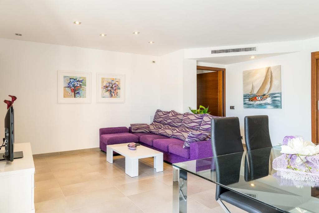 ポルト・ダ・ポリェンサにあるApartment Cormes By SunVillas Mallorcaのリビングルーム(紫色のソファ、ガラスのテーブル付)