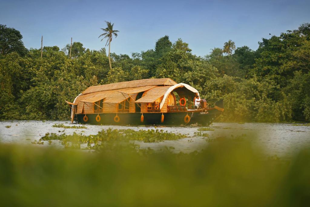 a boat with a bamboo roof on a river at Spice Coast Cruises - Houseboat in Alleppey