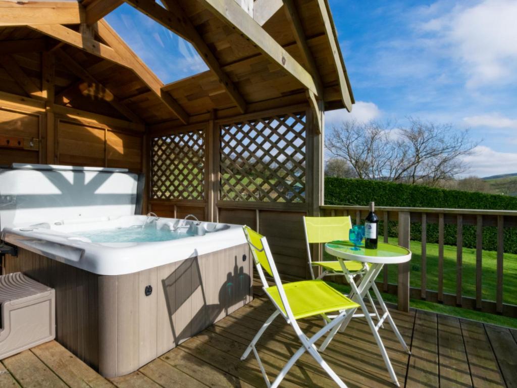 a deck with a hot tub and a table and chairs at Holiday Home Penrhy by Interhome in Devils Bridge