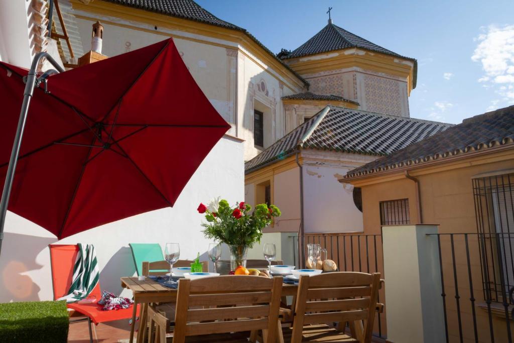 einen Tisch mit einem roten Regenschirm auf einer Terrasse in der Unterkunft Fresh, relax & sun Historic Center in Málaga